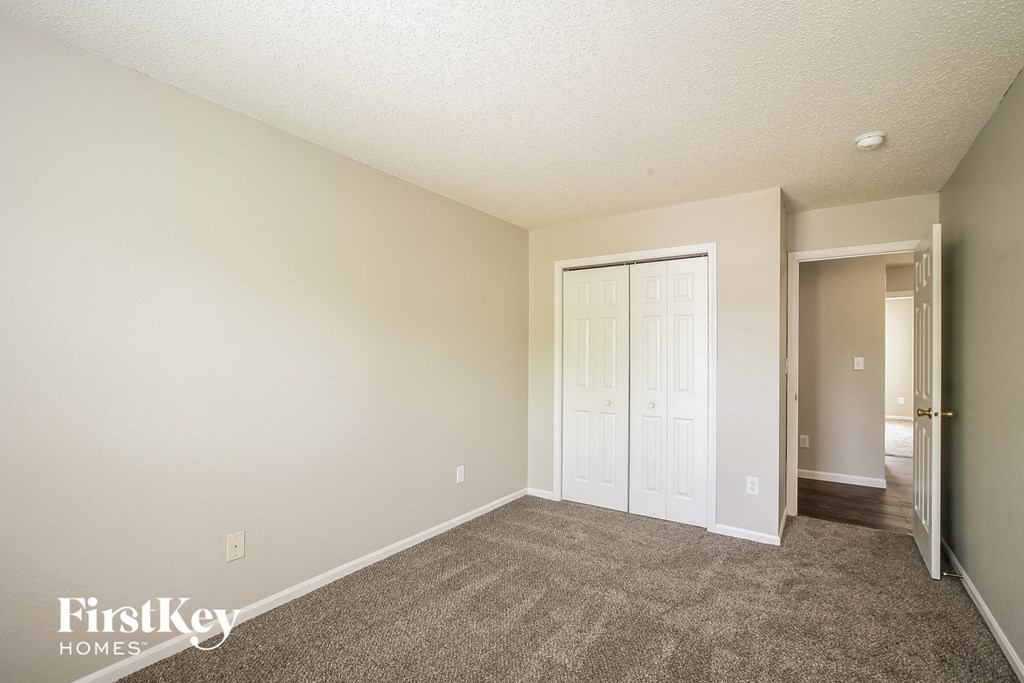 an empty living room with carpet and a door to a closet