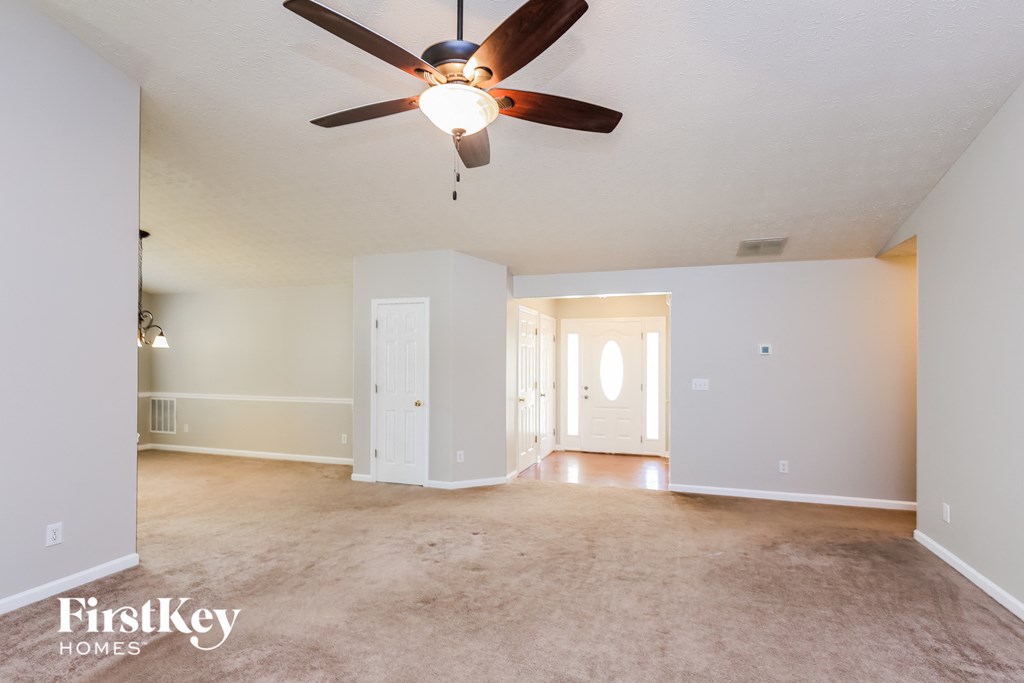 an empty living room with a ceiling fan and a carpet