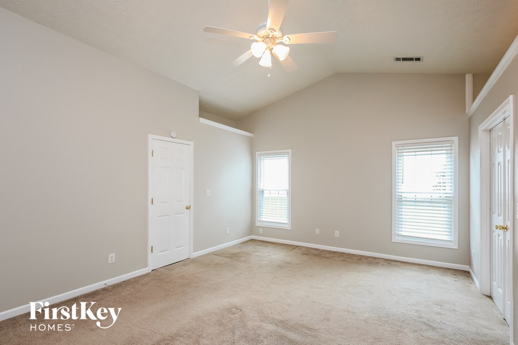 a spacious living room with a ceiling fan and a white door