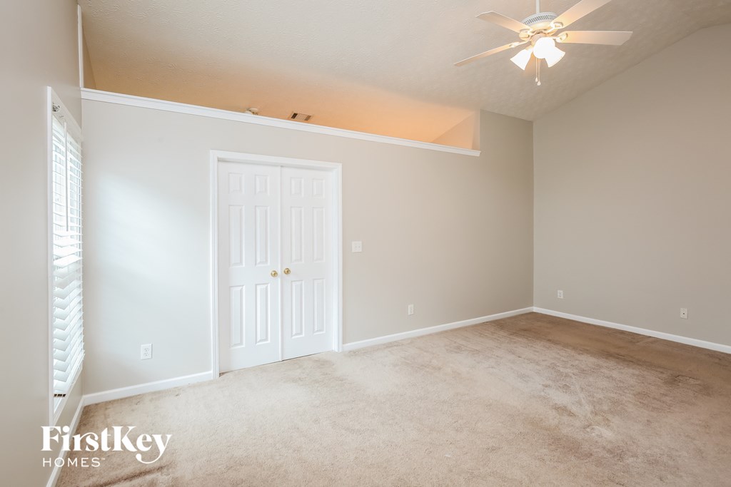 a empty living room with a ceiling fan and a white door
