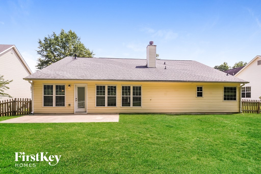 the front of a yellow house with a yard and grass