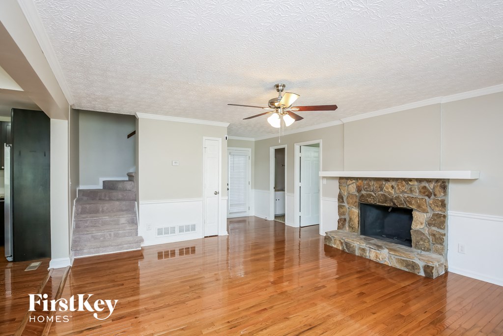 an empty living room with a fireplace and a ceiling fan