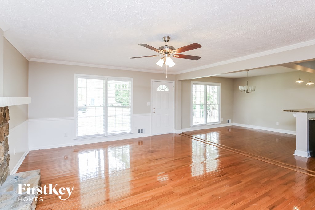 an empty living room with wood floors and a ceiling fan