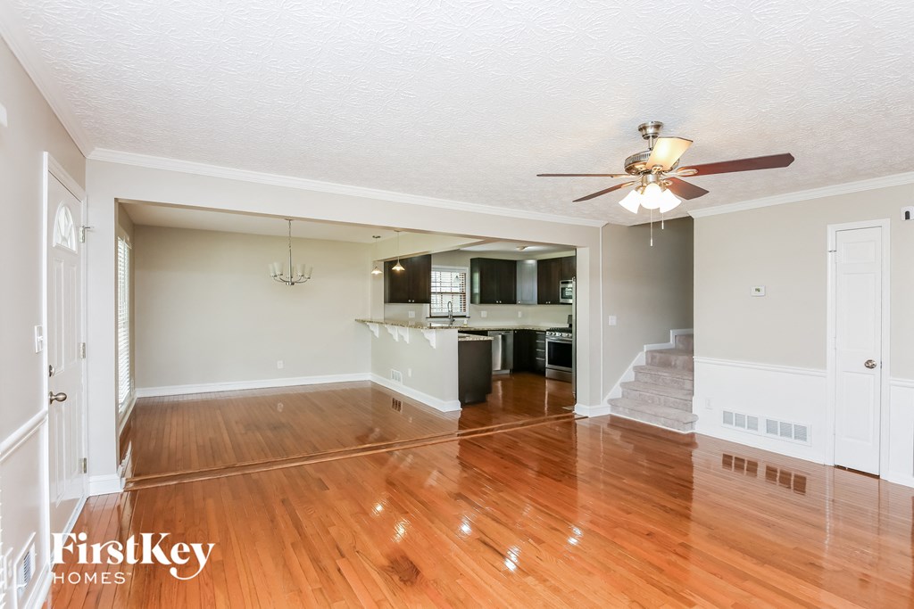 an empty living room and kitchen with wood floors and a ceiling fan