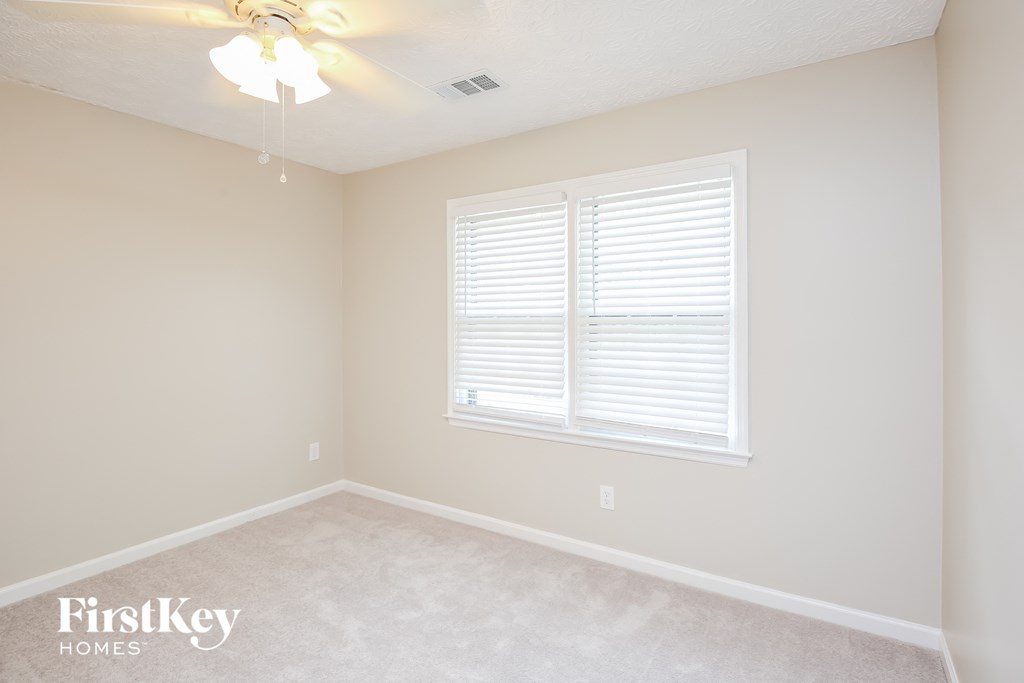 a bedroom with two windows and a ceiling fan