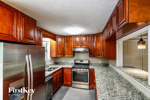 A kitchen with wooden cabinets and a stainless steel refrigerator.