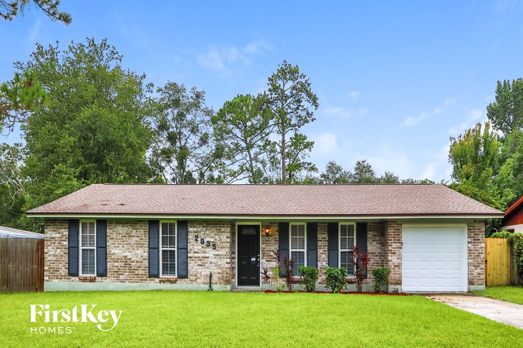 A house with a green lawn and trees in the background.