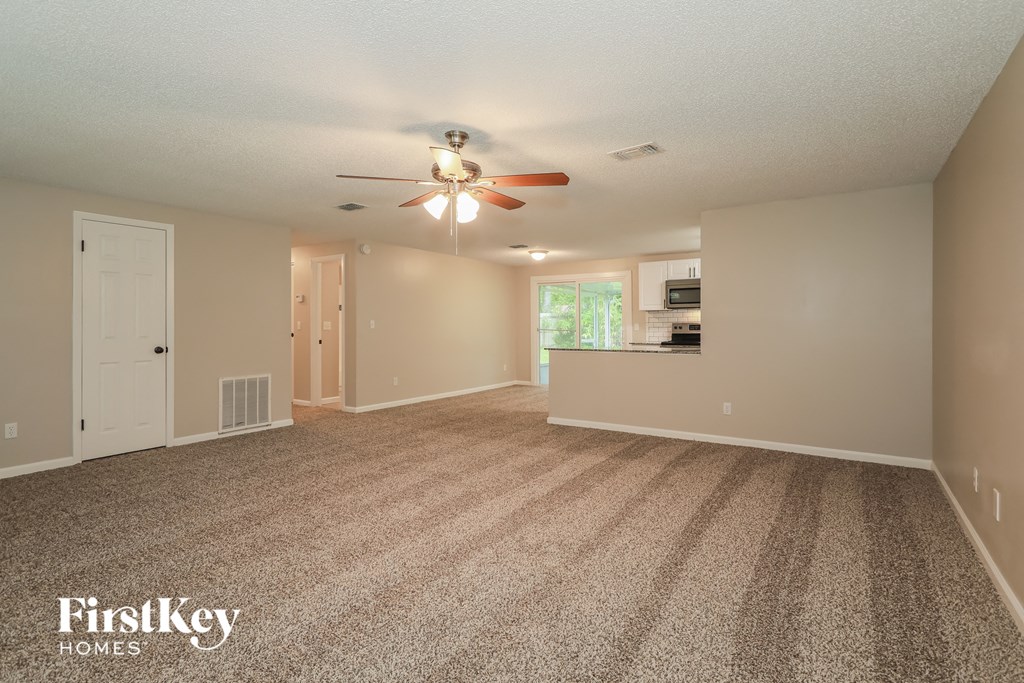 A spacious room with a carpeted floor and a ceiling fan.