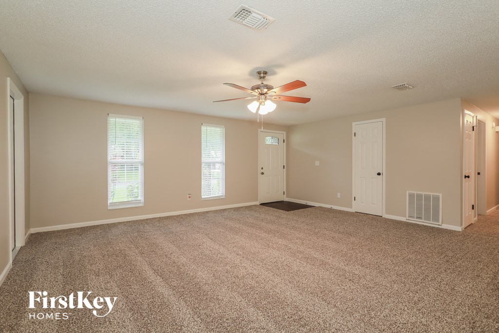 A spacious room with a fan and carpeted floor.
