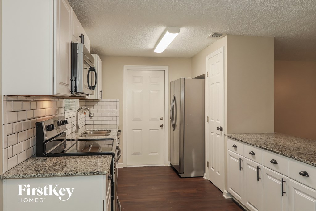 A kitchen with white cabinets and a granite countertop.
