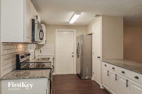 A kitchen with white cabinets and a granite countertop.