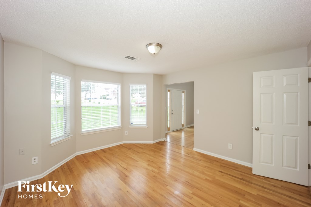 the living room and dining room with wood floors and white walls