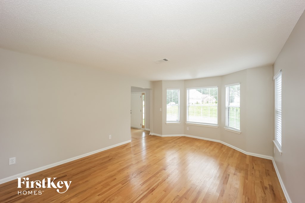 an empty living room with wood floors and white walls
