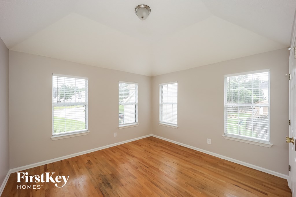 an empty room with wood floors and three windows