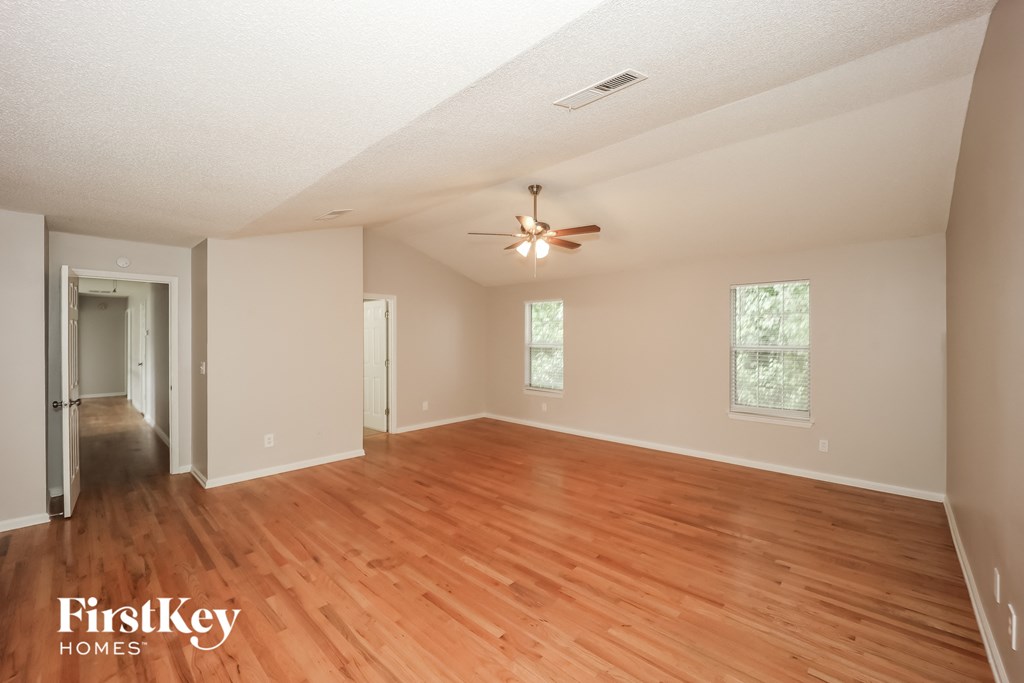 an empty living room with wood floors and a ceiling fan