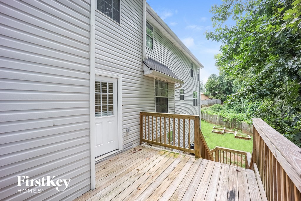 a backyard with a wooden deck and a white house