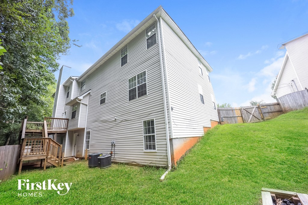the back of a white house with a yard and a fence