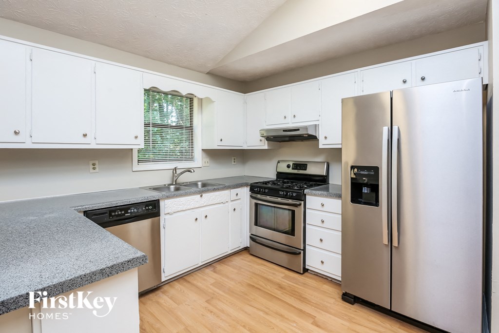 A kitchen with a refrigerator, stove, and sink.