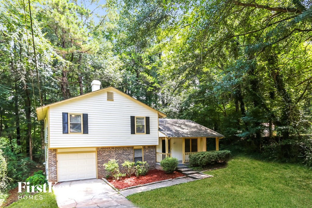 a small yellow and white house in the woods