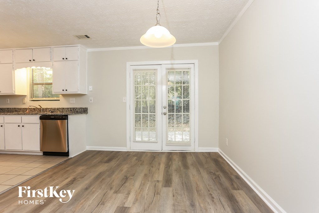 an empty kitchen with white cabinets and a door to a balcony