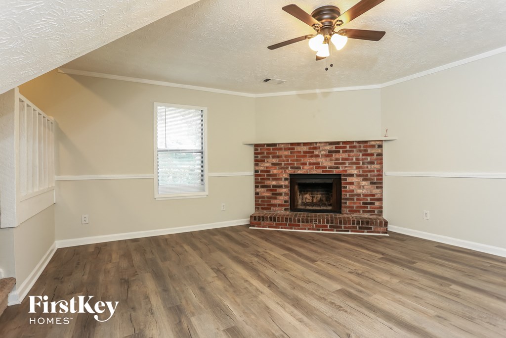 the living room of a house with a brick fireplace and wooden floors