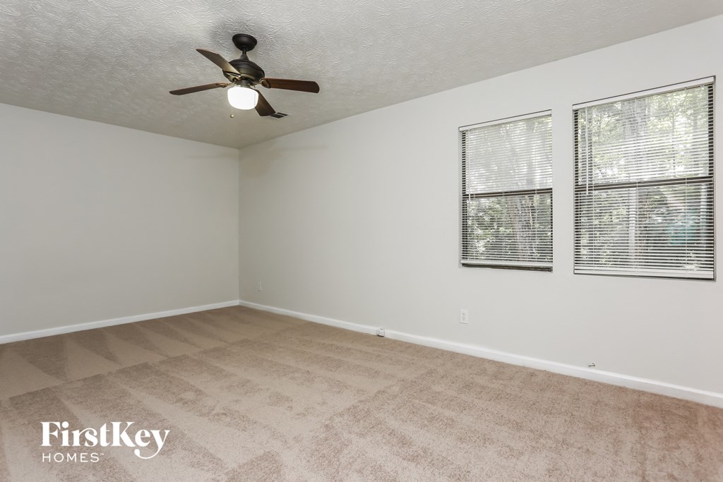 an empty living room with a ceiling fan and a window