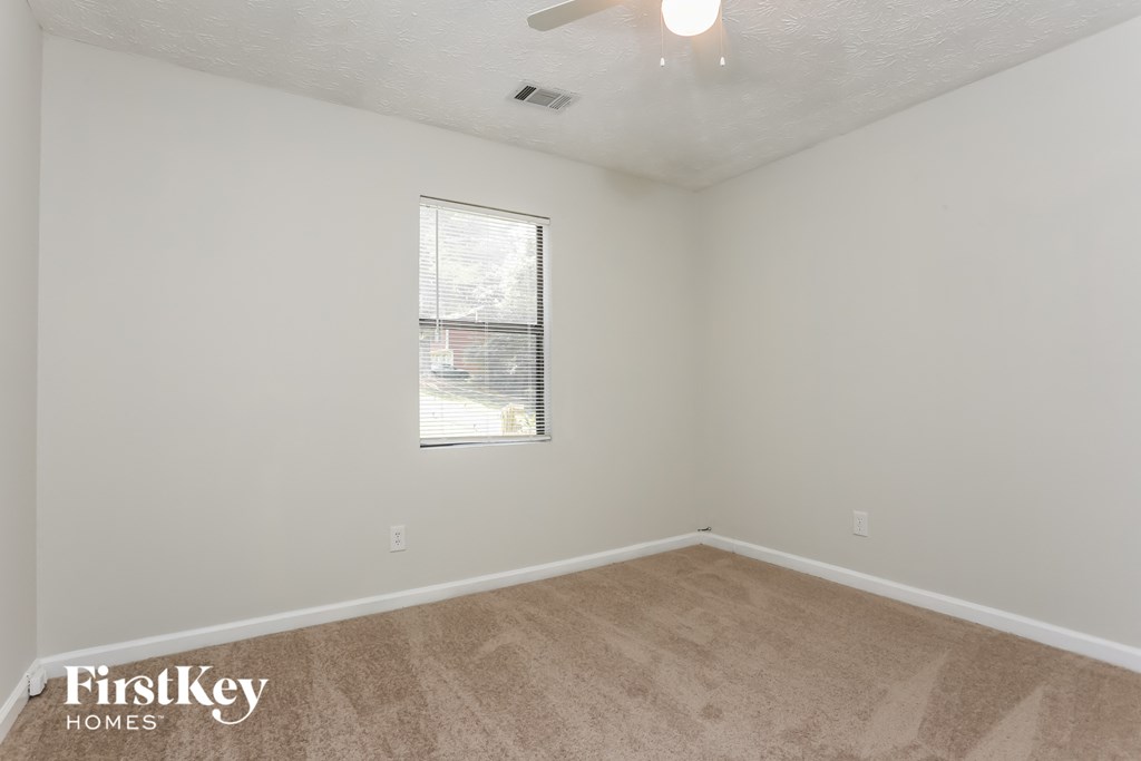 a bedroom with white walls and a window and a carpeted floor