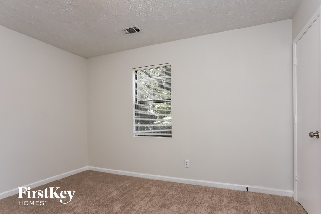the living room of an apartment with white walls and a window