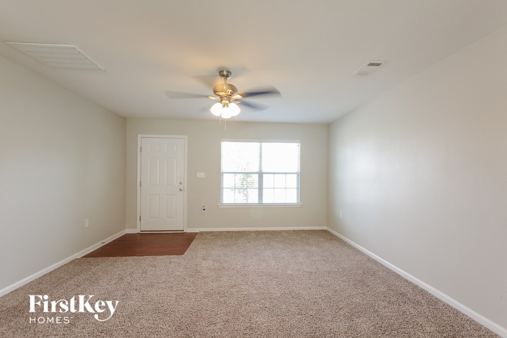 a empty living room with a ceiling fan and a window