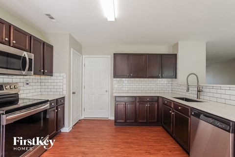 a kitchen with dark wood cabinets and white countertops and a wooden floor