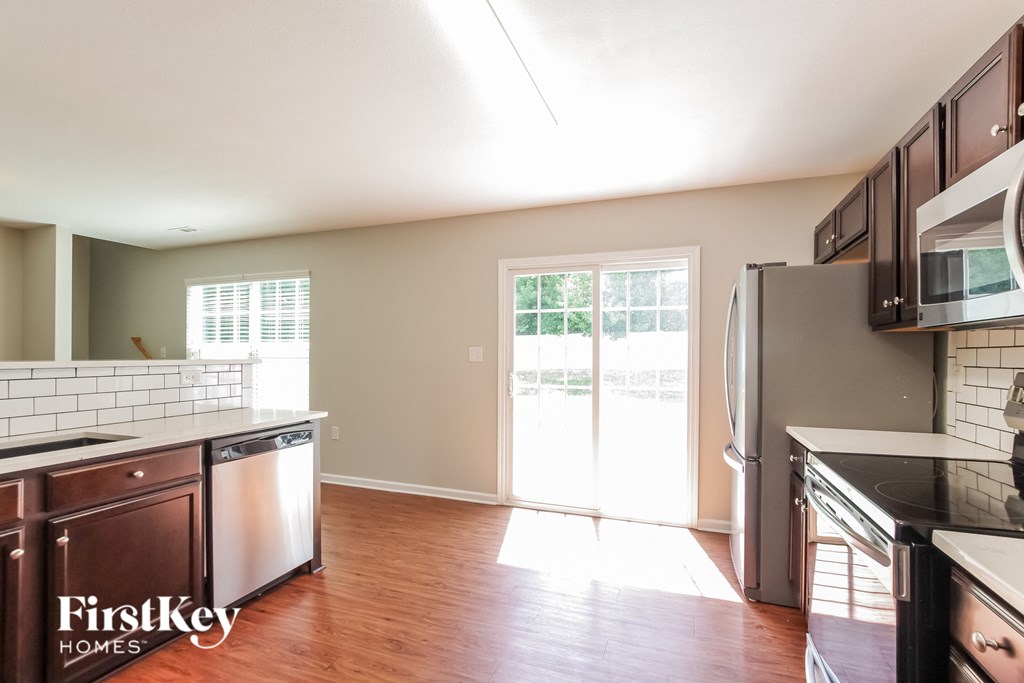 an empty kitchen with wood flooring and a door to a patio