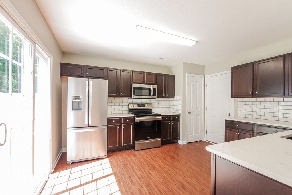an empty kitchen with wooden floors and stainless steel appliances