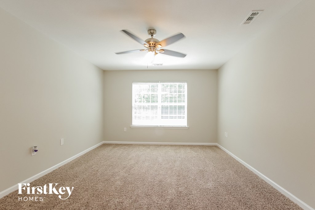 an empty room with a ceiling fan and a window