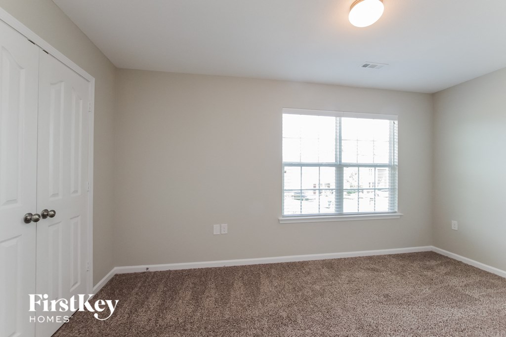 a bedroom with carpet and a window and a door
