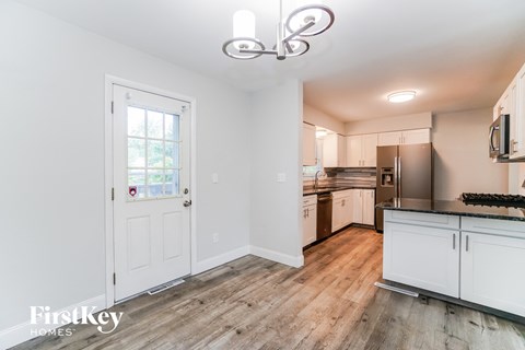 A kitchen with white cabinets and a wooden floor.