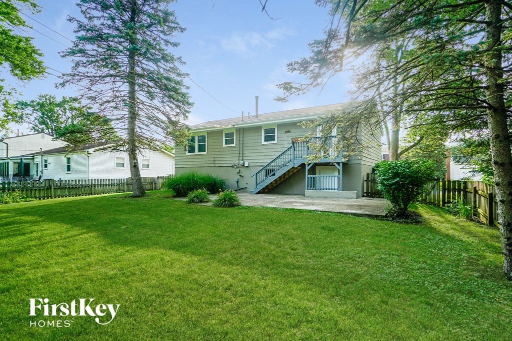 A house with a green lawn and trees in front of it.
