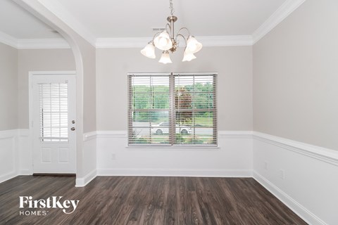 the living room of a home with white walls and wood floors
