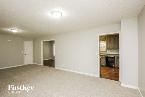 A spacious room with a kitchen area in the background.