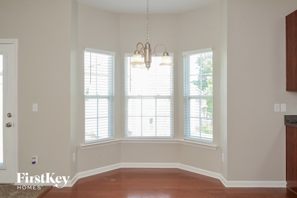 A room with a chandelier and three windows.