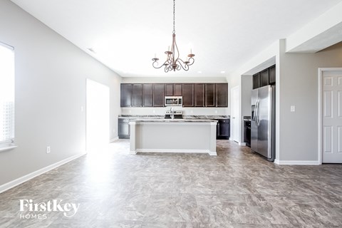 A spacious kitchen with a marble countertop and a chandelier hanging from the ceiling.