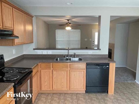 A kitchen with wooden cabinets and a black dishwasher.