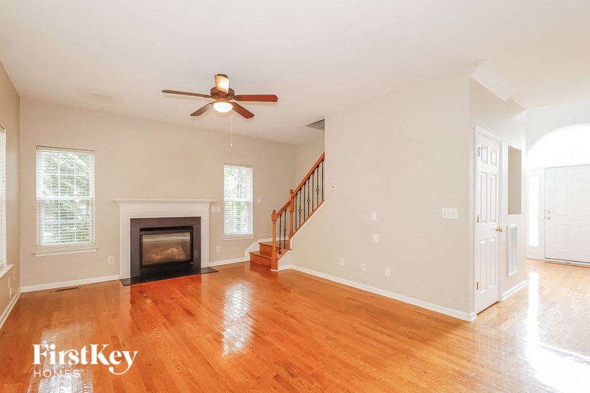 A spacious living room with a fireplace and a staircase.
