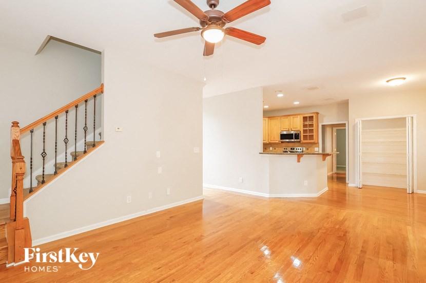 A spacious room with a wooden floor and a ceiling fan.