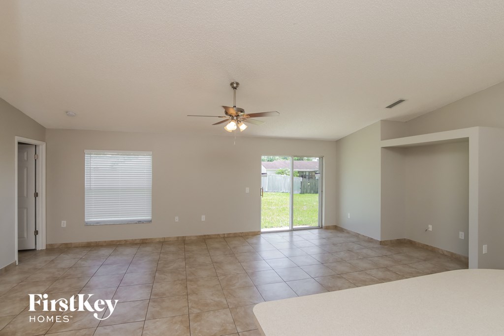 a spacious living room with tile flooring and a ceiling fan