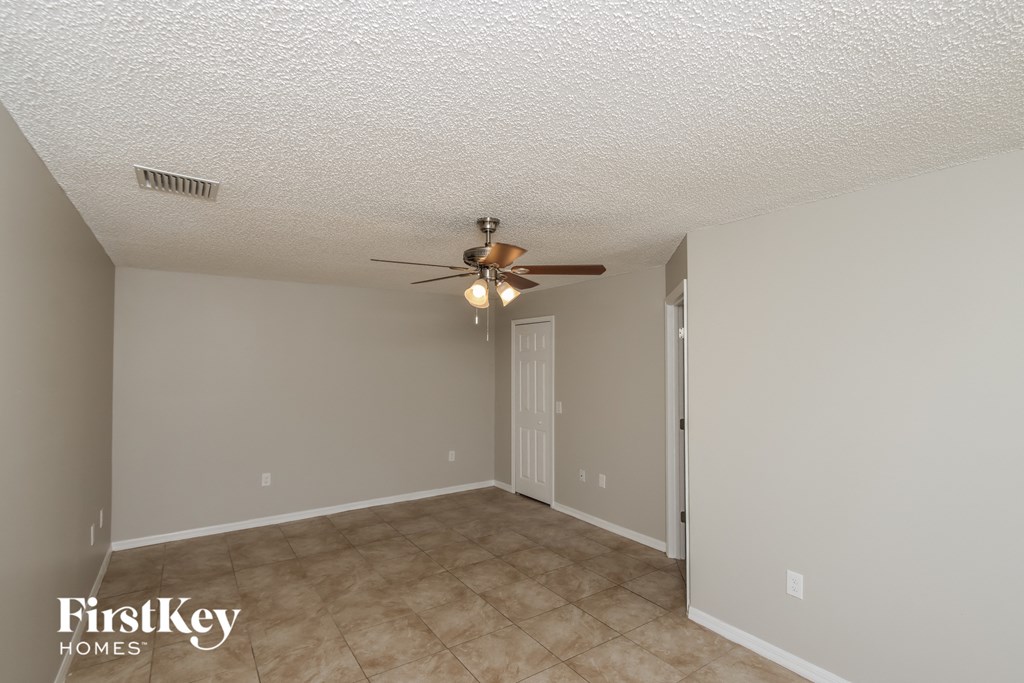 an empty living room with a ceiling fan and a door to a closet