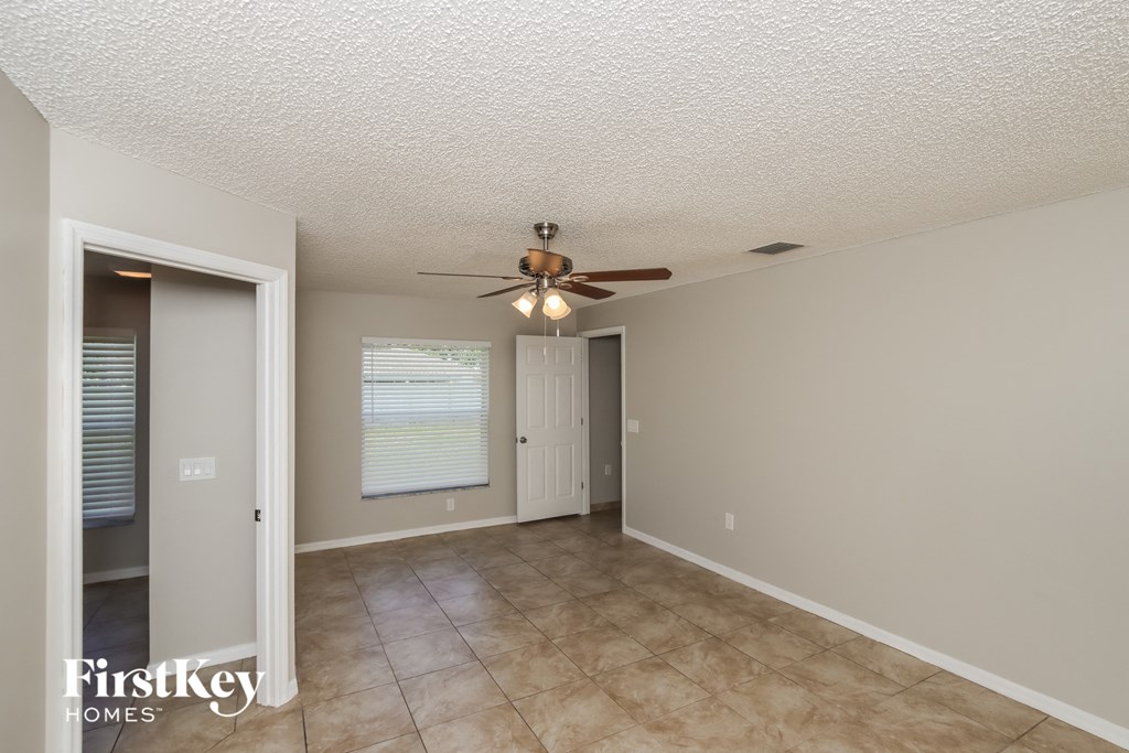 an empty living room with a ceiling fan and a door to a closet