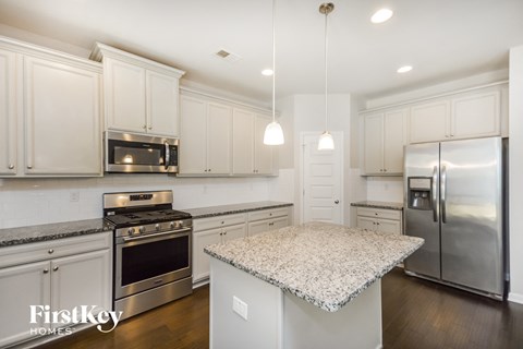 A kitchen with white cabinets and a granite countertop.