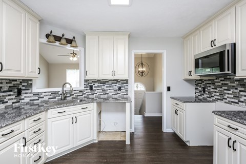 a white kitchen with marble counter tops and white cabinets