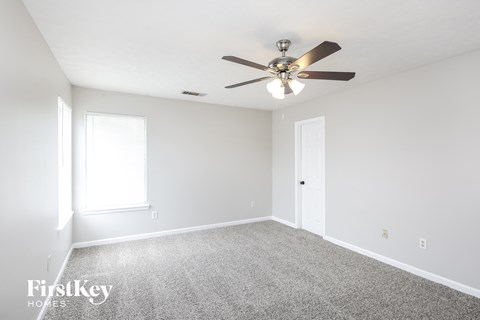 a bedroom with a ceiling fan and a carpet