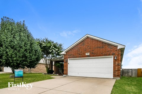 the front of a brick house with a white garage door